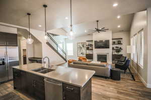 Kitchen with appliances with stainless steel finishes, sink, decorative light fixtures, and an island with sink