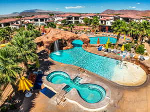 View of pool featuring pool water feature, a hot tub, a mountain view, and a patio