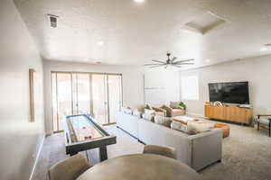 Living room with light carpet, ceiling fan, and a textured ceiling