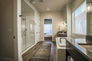 Bathroom featuring ceiling fan, wood-type flooring, plus walk in shower, and vanity