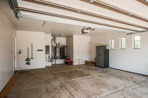 Garage featuring a garage door opener, electric panel, and gas water heater