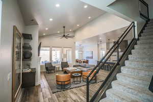 Living room featuring ceiling fan, wood-type flooring, and high vaulted ceiling