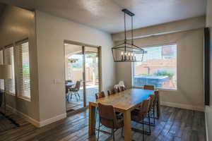 Dining space with dark wood-type flooring, a textured ceiling, and plenty of natural light