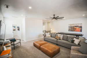 Living room with ceiling fan, carpet floors, and a textured ceiling