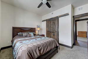 Bedroom with ceiling fan, carpet flooring, and a barn door