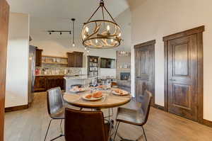 Dining room featuring a notable chandelier, a fireplace, high vaulted ceiling, and light wood-type flooring