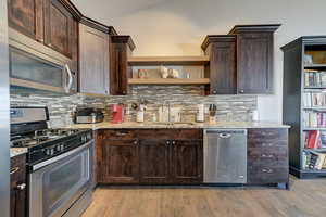 Kitchen with light stone countertops, appliances with stainless steel finishes, and sink