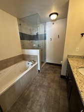 Full bathroom with vanity, separate shower and tub, a textured ceiling, and toilet