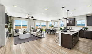 Kitchen featuring pendant lighting, sink, an island with sink, and dark brown cabinets