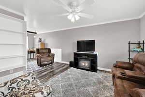 Living room featuring crown molding, ceiling fan, and wood-type flooring