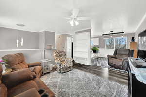 Living room with hardwood / wood-style floors, track lighting, ornamental molding, and a textured ceiling