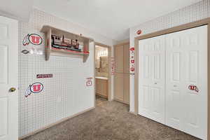 Corridor featuring sink, light carpet, and a textured ceiling