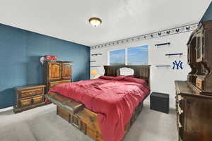 Bedroom with light colored carpet and a textured ceiling