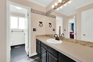 Bathroom featuring crown molding, vanity, toilet, and decorative backsplash