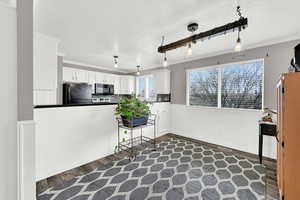 Kitchen with hanging light fixtures, dark hardwood / wood-style floors, white cabinets, and black appliances