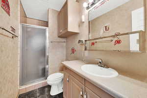 Bathroom featuring vanity, tile patterned flooring, a shower with shower door, and toilet