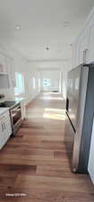 Kitchen featuring stainless steel appliances, light hardwood / wood-style floors, and white cabinets