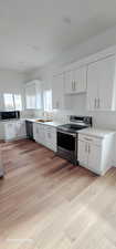 Kitchen with stainless steel appliances, white cabinetry, and sink