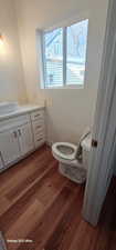 Bathroom with hardwood / wood-style flooring, vanity, and toilet