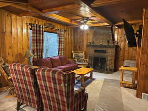 Furnished Living room with a fireplace, wooden walls, ceiling fan, wood ceiling, and beam ceiling