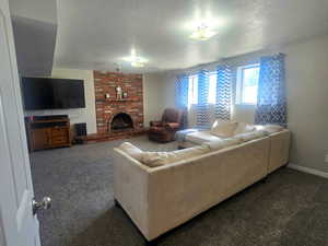 Carpeted living room with a brick fireplace and a textured ceiling