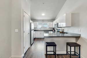 Kitchen featuring white cabinetry, appliances with stainless steel finishes, a breakfast bar, and kitchen peninsula