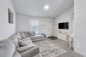 Carpeted living room featuring lofted ceiling