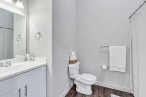 Bathroom with hardwood / wood-style flooring, vanity, and toilet