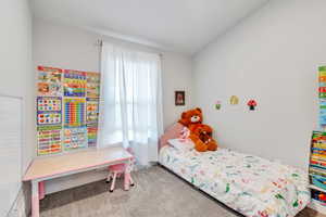 Bedroom with lofted ceiling and carpet floors