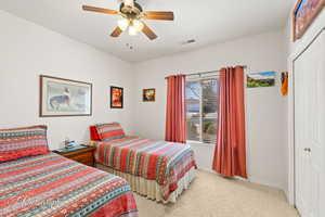 Carpeted bedroom featuring ceiling fan and a closet