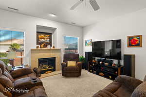 Carpeted living room featuring a fireplace and ceiling fan