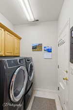 Laundry area featuring cabinets, separate washer and dryer, a textured ceiling, and light tile patterned floors