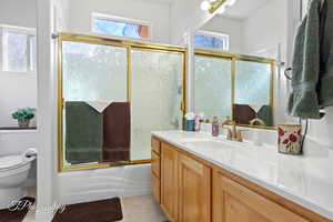 Full bathroom with tile patterned flooring, plenty of natural light, toilet, and combined bath / shower with glass door