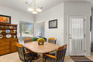 Dining area with light carpet and a notable chandelier