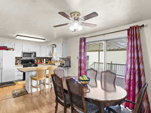 Dining room featuring ceiling fan, light hardwood / wood-style flooring, and a textured ceiling