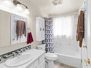 Full bathroom with tasteful backsplash, vanity, shower / tub combo, and toilet