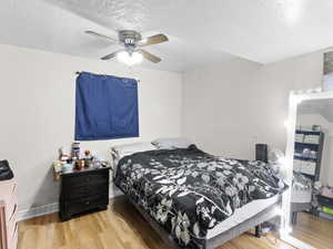 Bedroom with hardwood / wood-style floors, a textured ceiling, and ceiling fan