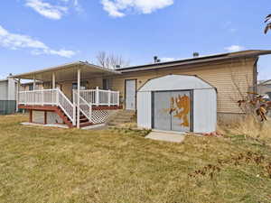 Back of house with a storage shed, covered porch, and a lawn