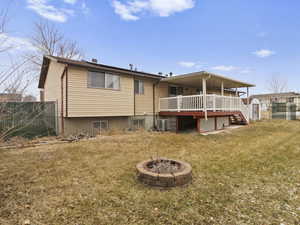 Rear view of house with a yard, cooling unit, a deck, and a fire pit