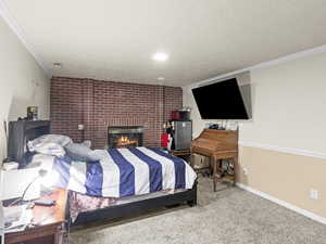 Bedroom featuring ornamental molding, carpet flooring, a brick fireplace, and a textured ceiling