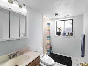 Bathroom with tile patterned flooring, vanity, toilet, a textured ceiling, and a shower with curtain