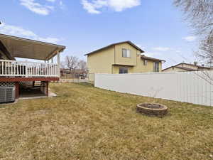 View of yard with central AC unit, a deck, and an outdoor fire pit