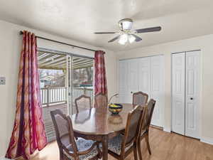 Dining space with ceiling fan, a textured ceiling, and light wood-type flooring