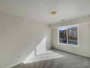 Carpeted spare room featuring a textured ceiling