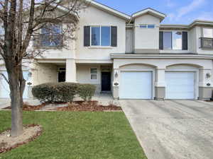 Townhome / multi-family property featuring a garage and a front yard