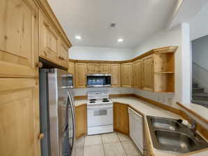 Kitchen featuring sink, light tile patterned floors, light brown cabinets, and appliances with stainless steel finishes