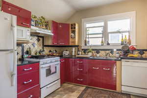 Kitchen with lofted ceiling, sink, white appliances, and decorative backsplash