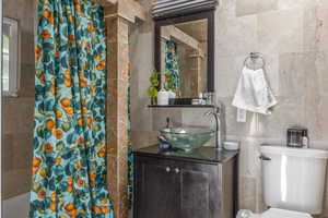 Bathroom featuring vanity, tile walls, and toilet