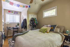 Bedroom featuring ceiling fan, wood-type flooring, vaulted ceiling, and a closet