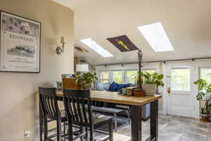 Dining space with lofted ceiling, a healthy amount of sunlight, and light tile patterned flooring